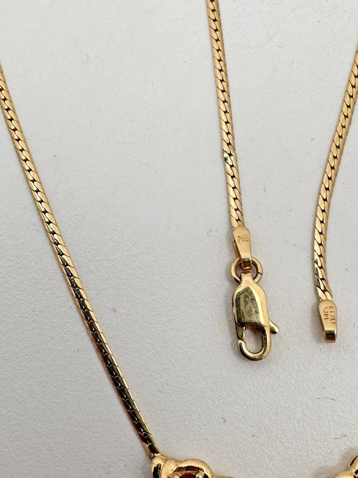 17-inch 14K yellow gold necklace, adorned with 7 oval 4 mm x 6 mm rubies and 3 round diamonds