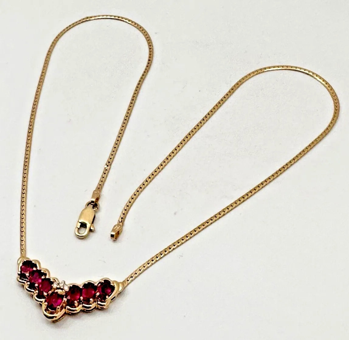 17-inch 14K yellow gold necklace, adorned with 7 oval 4 mm x 6 mm rubies and 3 round diamonds