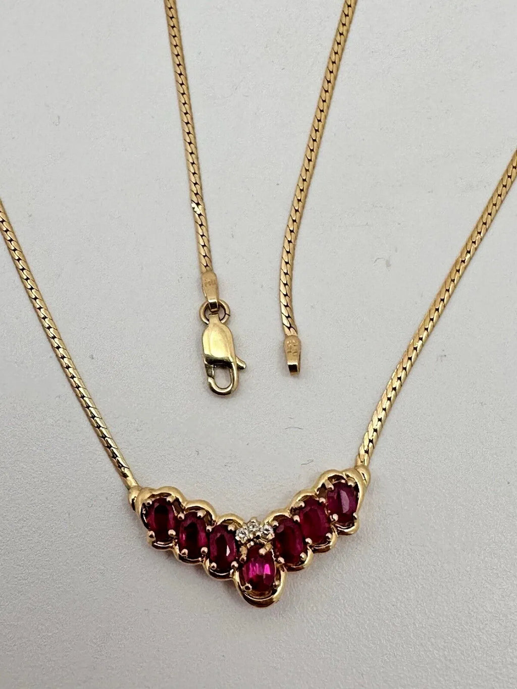 17-inch 14K yellow gold necklace, adorned with 7 oval 4 mm x 6 mm rubies and 3 round diamonds