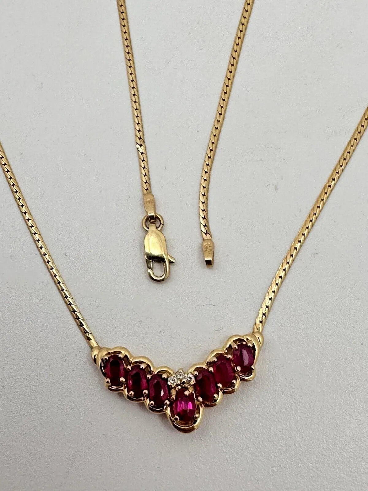 17-inch 14K yellow gold necklace, adorned with 7 oval 4 mm x 6 mm rubies and 3 round diamonds
