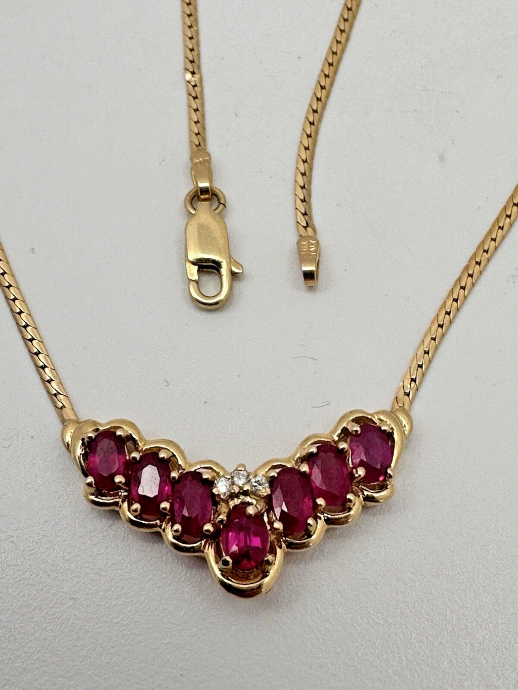 17-inch 14K yellow gold necklace, adorned with 7 oval 4 mm x 6 mm rubies and 3 round diamonds