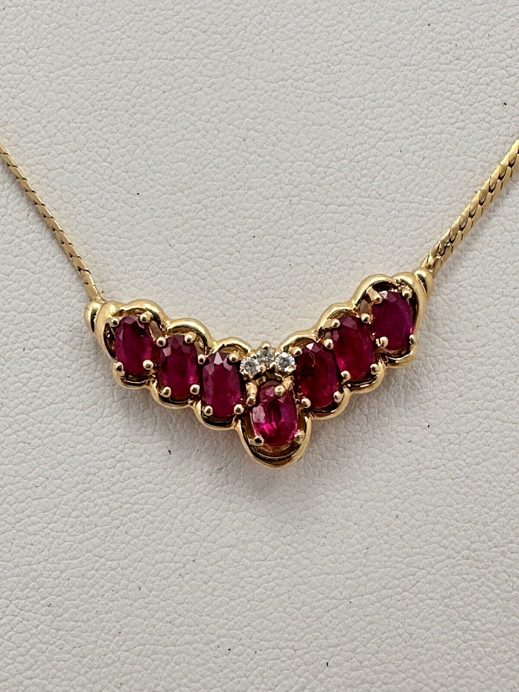 17-inch 14K yellow gold necklace, adorned with 7 oval 4 mm x 6 mm rubies and 3 round diamonds