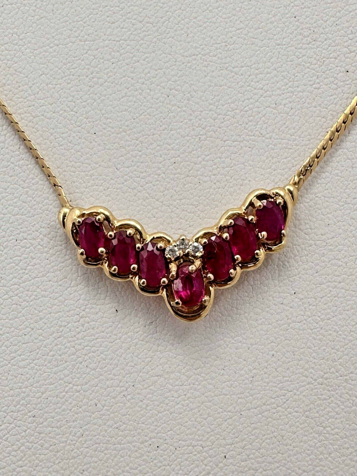 17-inch 14K yellow gold necklace, adorned with 7 oval 4 mm x 6 mm rubies and 3 round diamonds