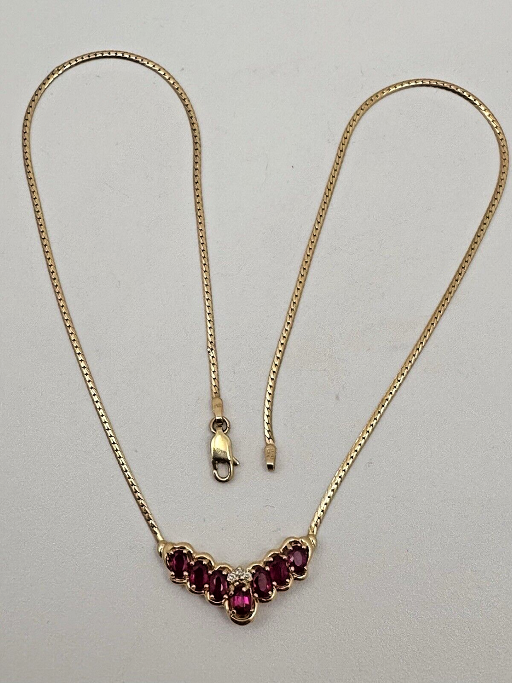 17-inch 14K yellow gold necklace, adorned with 7 oval 4 mm x 6 mm rubies and 3 round diamonds