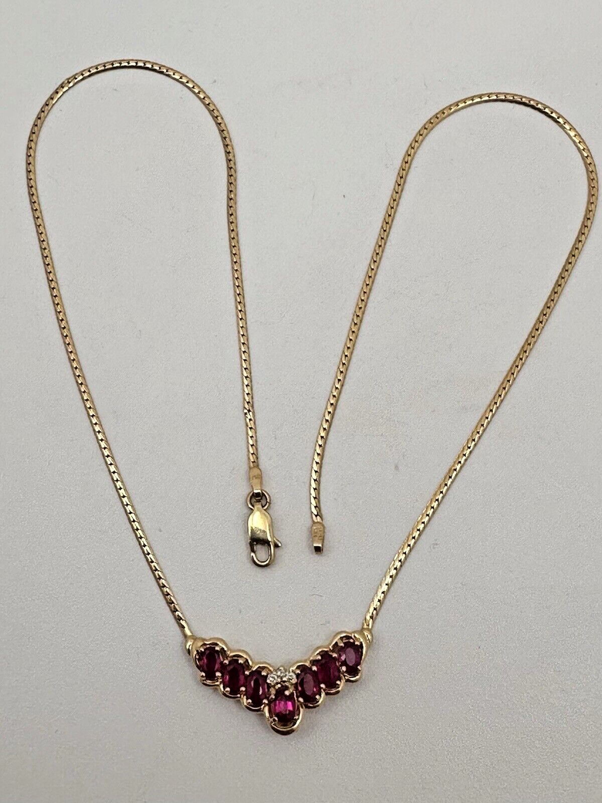 17-inch 14K yellow gold necklace, adorned with 7 oval 4 mm x 6 mm rubies and 3 round diamonds