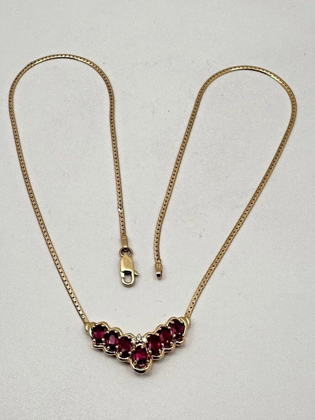 17-inch 14K yellow gold necklace, adorned with 7 oval 4 mm x 6 mm rubies and 3 round diamonds