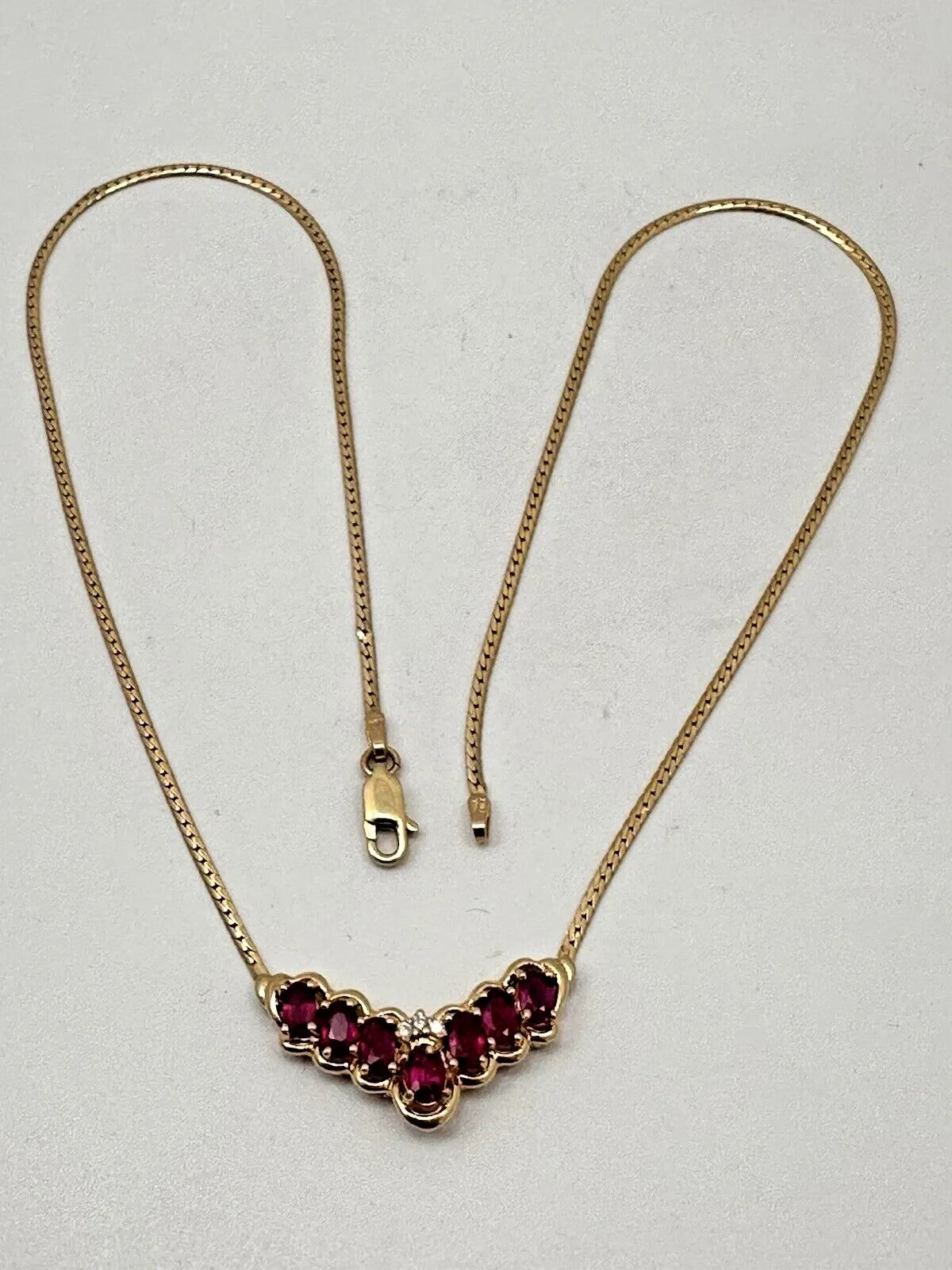 17-inch 14K yellow gold necklace, adorned with 7 oval 4 mm x 6 mm rubies and 3 round diamonds